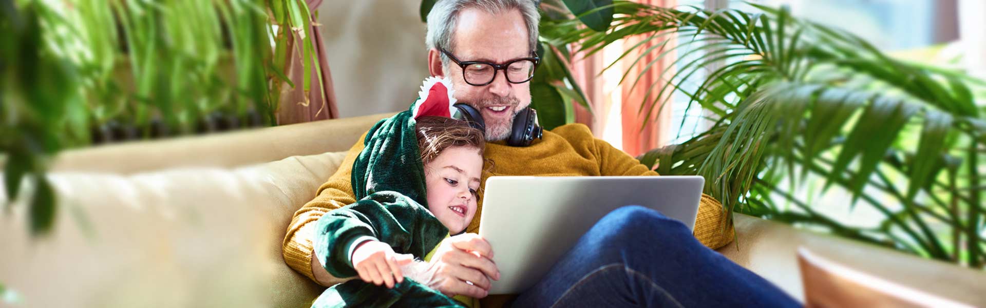 A man is sitting on a couch with his young child, enjoying a beautiful, sunny day.