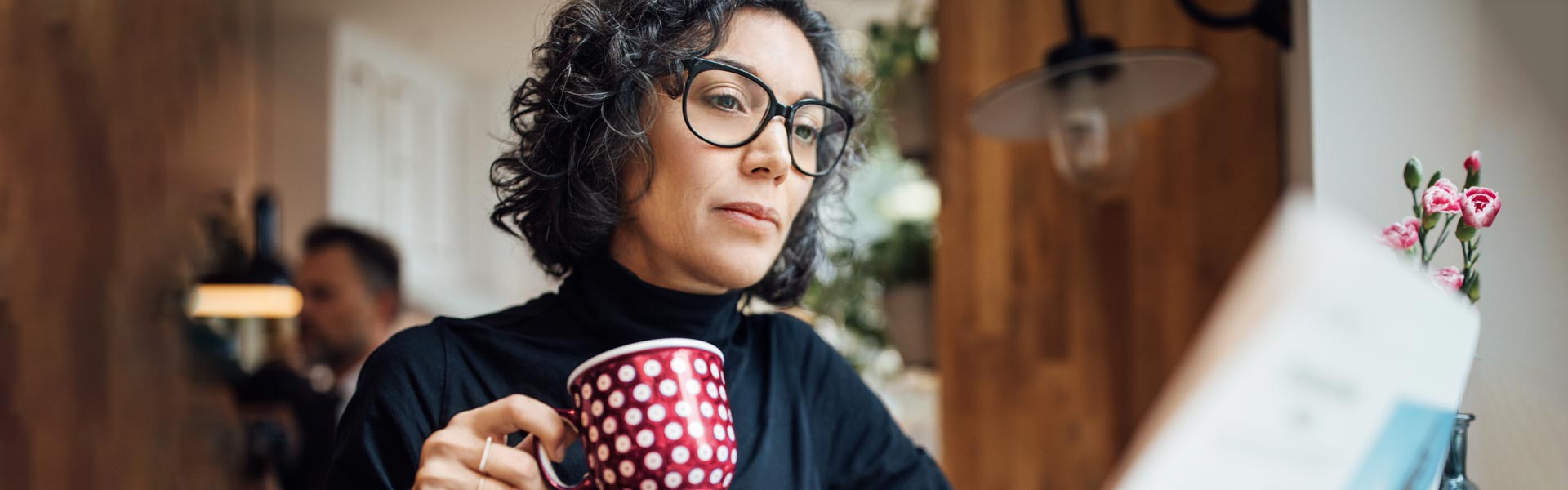 A woman enjoying a warm beverage while looking at her laptop. 