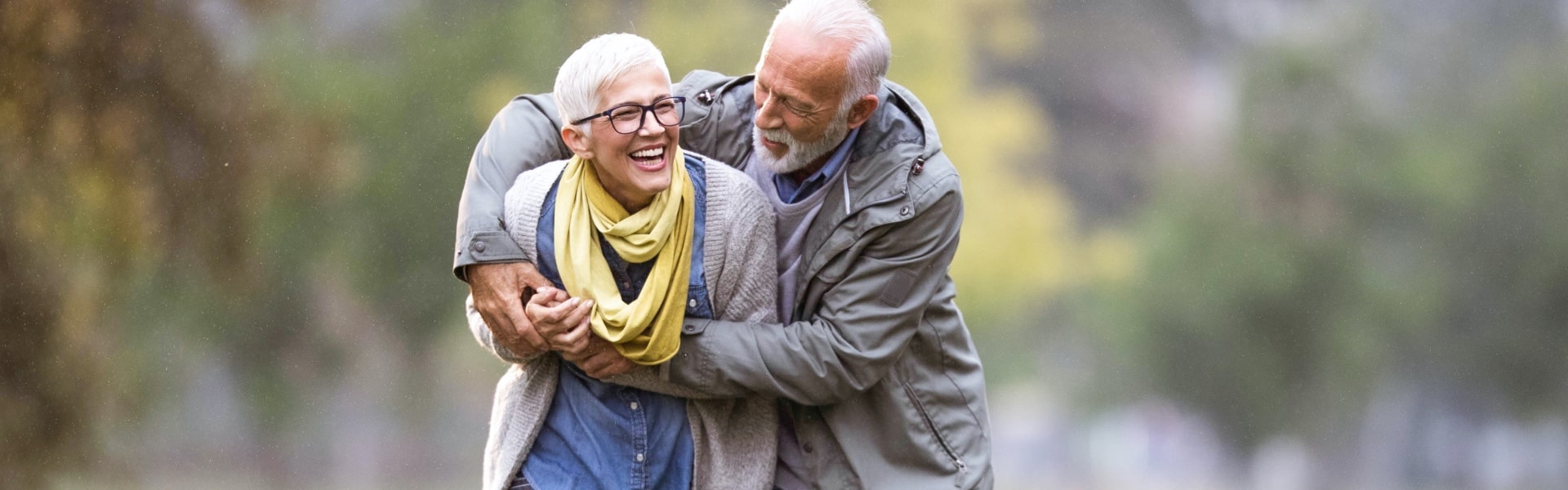 Happy romantic senior couple hugging and enjoying retirement outside.
