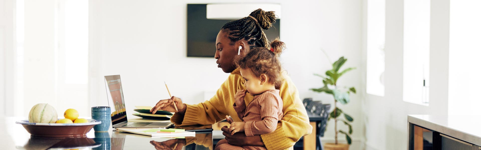A young woman looks at information on her laptop and takes notes for an assignment.
