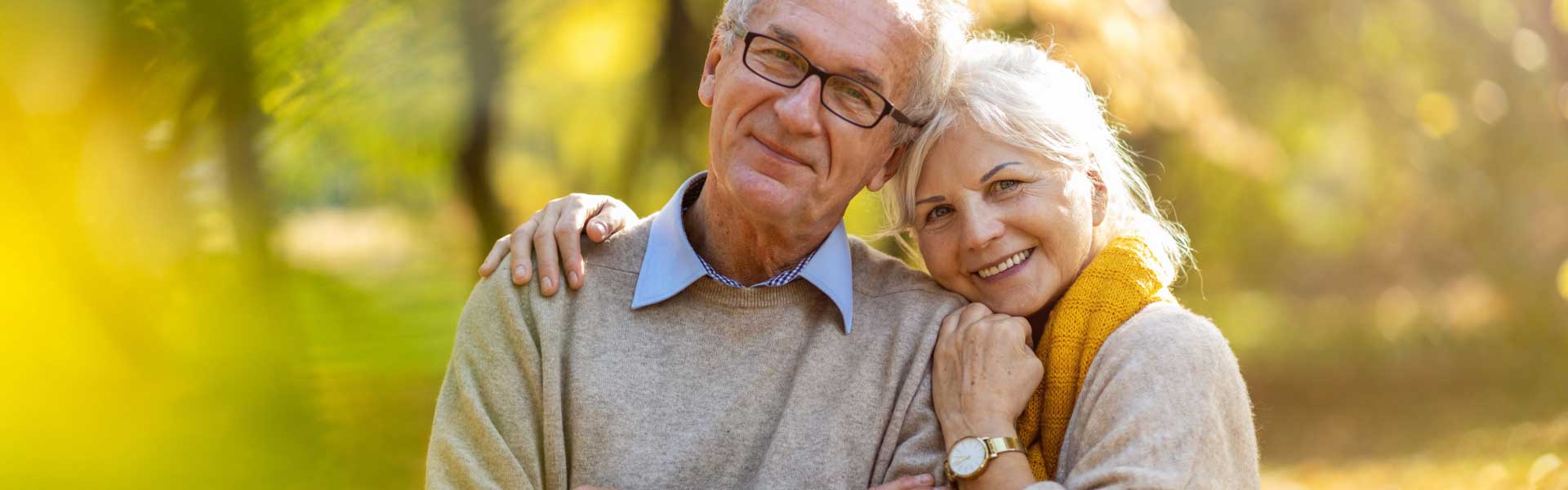 Retired couple holding each other and facing camera.