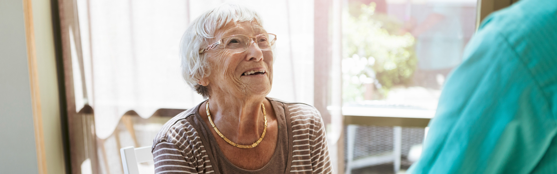 An older woman is smiling up at someone out of the frame.
