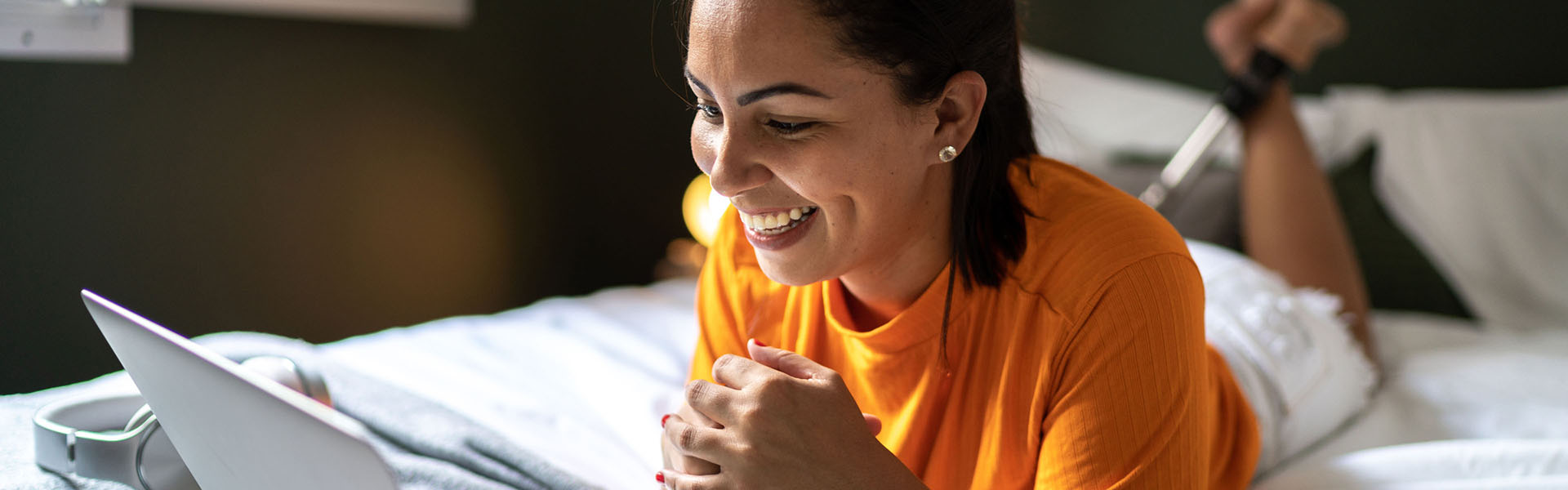 A woman is smiling at a laptop.	